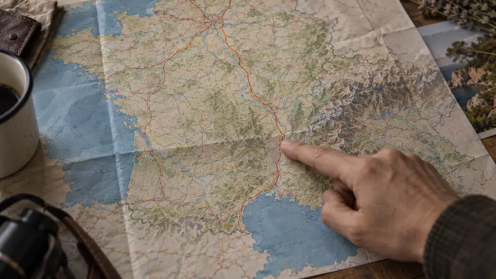 editorial photograph of a finger tracing the A6, A7 and A9 route from Paris through Lyon and Orange to Montpellier on a folded motorway map, no readable text or logos